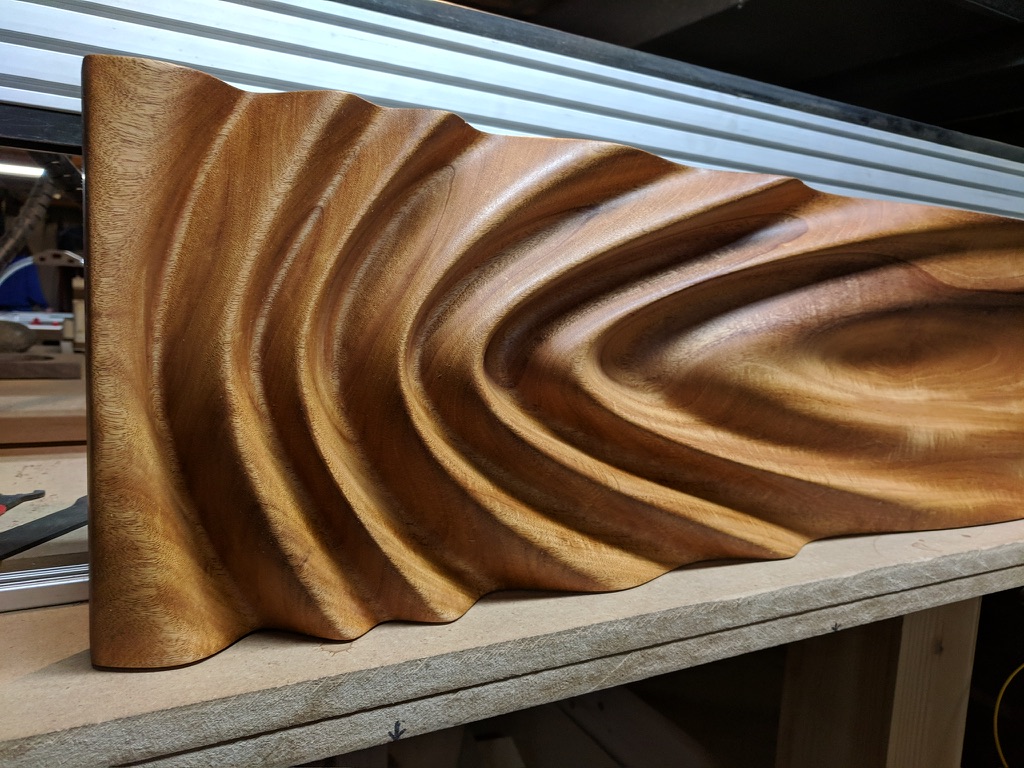 CNC-carved wave relief panel in warm amber tones, deep grain texture